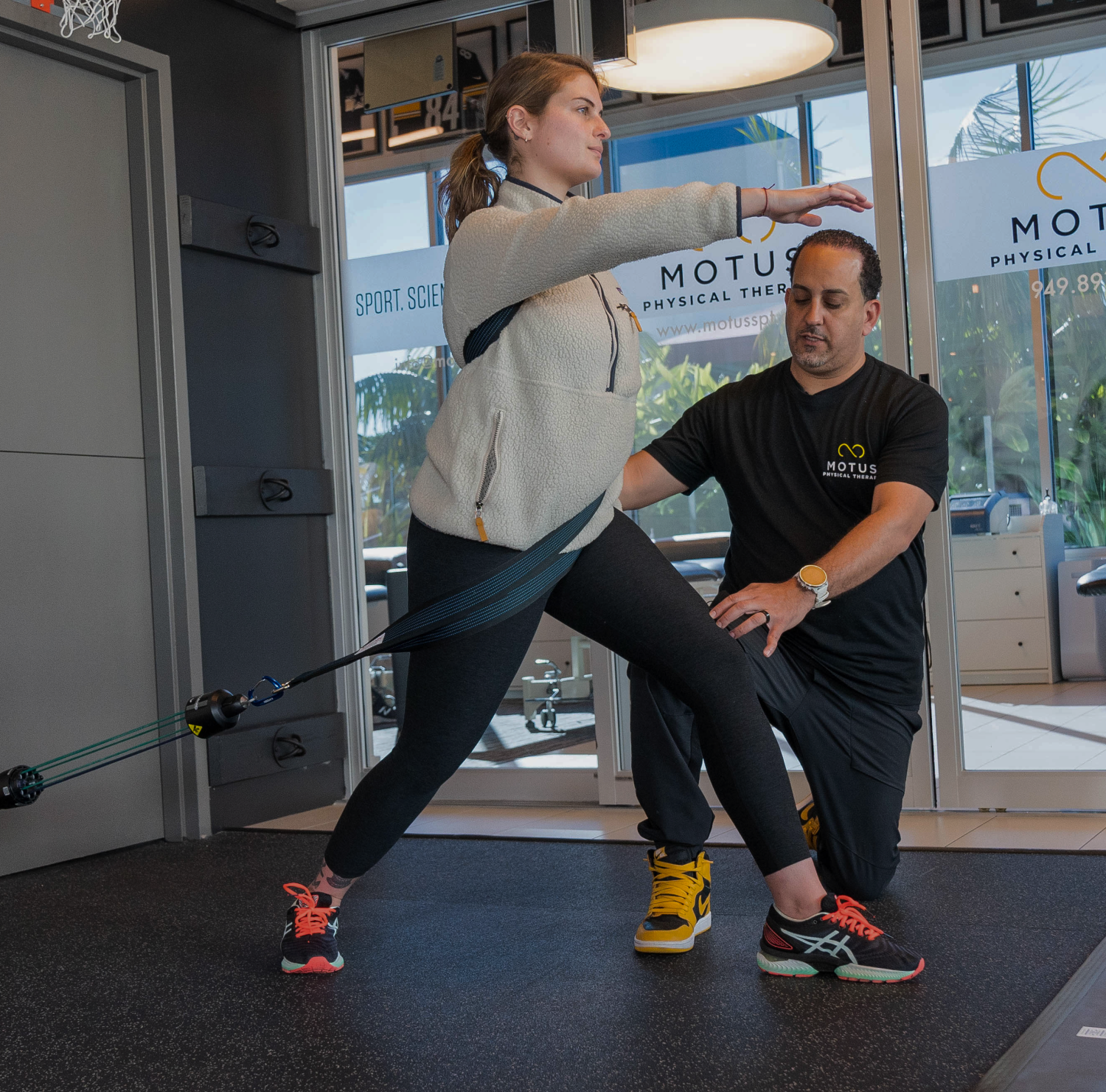 Physical therapist assisting a woman with resistance band exercises for strength and balance at Motus Physical Therapy